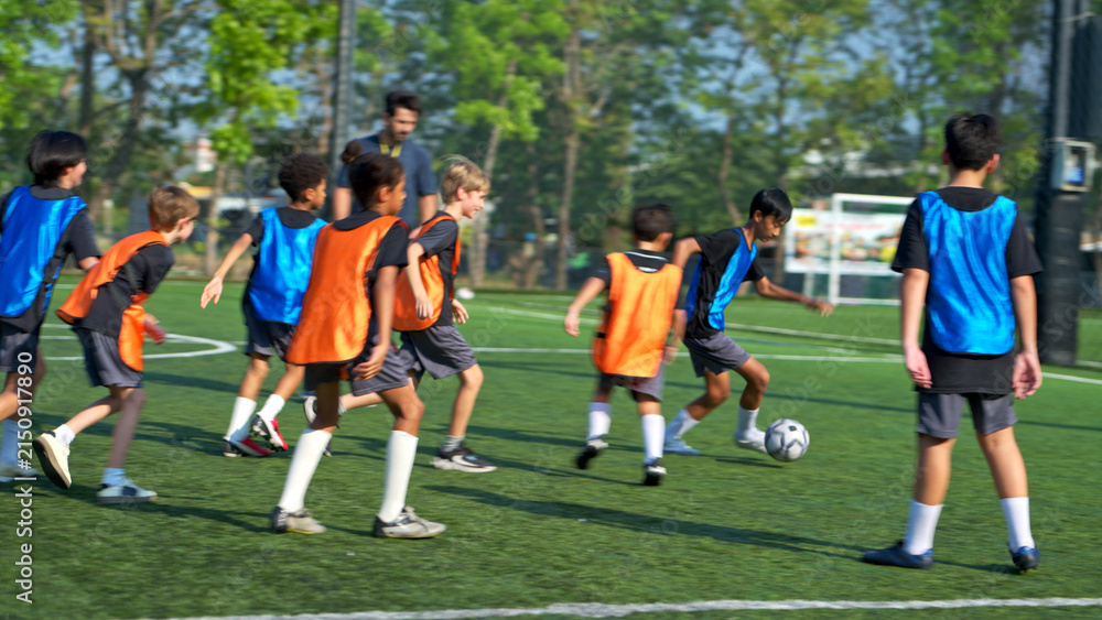 Obraz premium Football coach training international school students on the field,