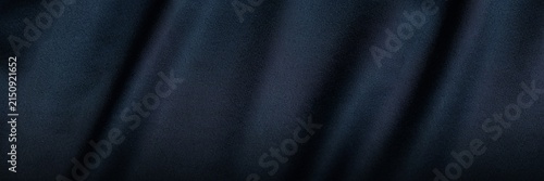 Navy blue velvet fabric texture with soft ripples. Elegant dark blue textile background with luxury silk sheen. Deep indigo cloth material for fashion design and interior upholstery decor.
