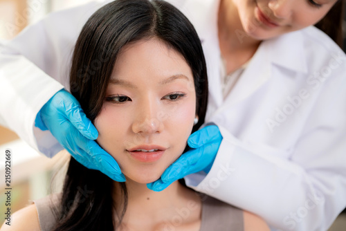Young asian woman aesthetic doctor examining skin face of woman patient in clinical office, specialist touching beauty ace for cosmetic treatment consultation, evaluating diagnostic skin facial.