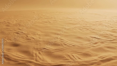 Slow pan of desert sand ripples shifting across dune plain in warm golden light at sunset