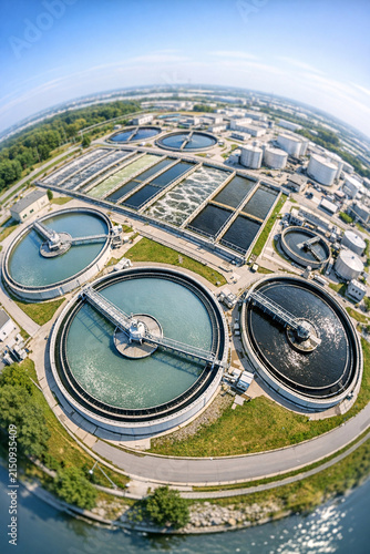 This image shows a large-scale wastewater treatment plant. It features multiple circular processing tanks arranged in a circular pattern, designed to handle industrial and municipal wastewater flows.