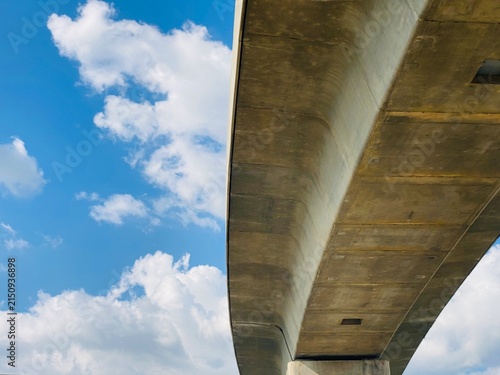 Curved concrete flyover bridge structure against cloudy blue sky