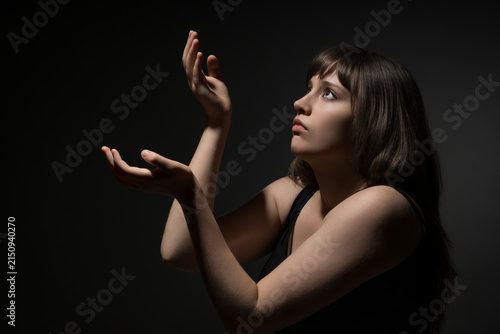 Fotografie Young woman looking up with hands raised in prayer or wonder