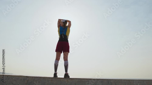 Sunrise glows behind a woman stretching on the beach. Three keyframes show back, side, and full-body views. She wears a blue top and red shorts. Calm waters stretch toward the distant horizon