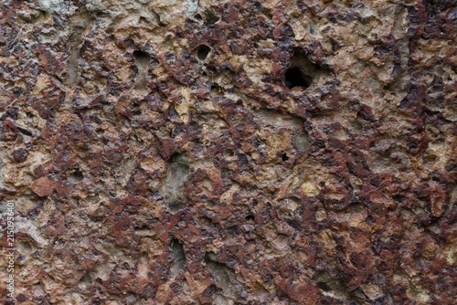 Photography stone wall with pitted porous surface and reddish brown tone.