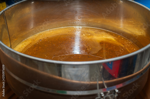 Freshly extracted raw honey filling a stainless steel container