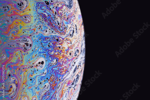 Large hemispheric soap film with sweeping pastel blues and warm highlights set against a stark black field.