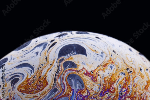 Textural macro of soap membranes with warm gold and ink‑black veins forming dynamic, organic shapes.
