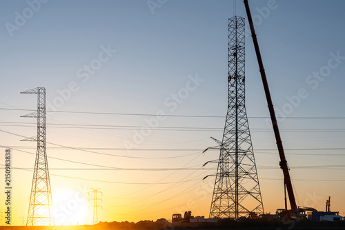 Crane Erecting Steel Transmission Tower Near Power Lines