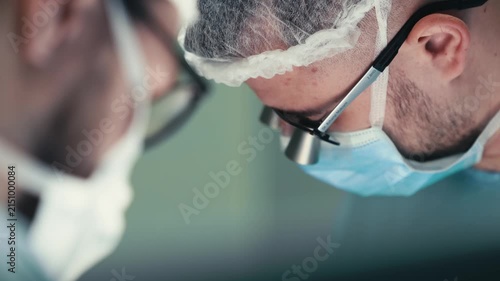 Portrait of surgeons collaborating during a demanding surgical procedure. Concept professional medical teamwork, surgical technology, precision care and advanced medicine.