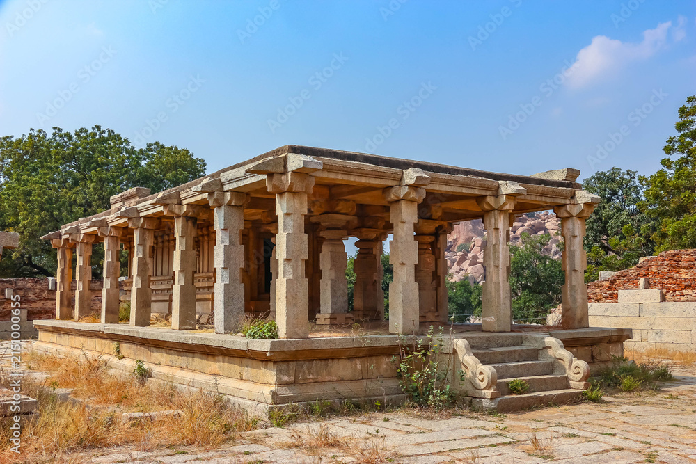 Fototapeta premium Ancient stone temple ruins and historic carved architecture in Hampi, India. Beautiful landscape with archaeological site, cultural heritage landmark and popular international tourist destination.