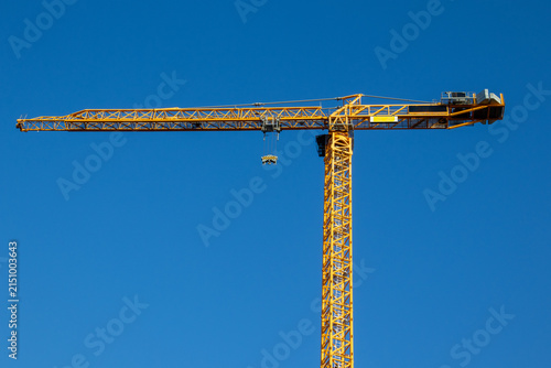 Tower crane full profile with jib and mast against clear blue sky