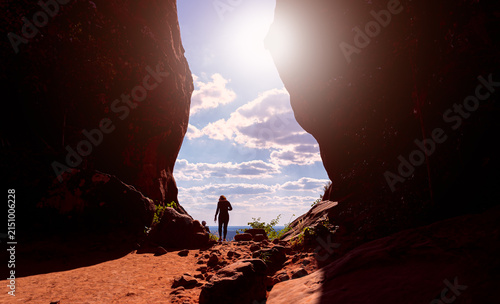 Sun flare with silhouette. Two people are standing in the gap between two large rocks and taking a selfie as a memorial of their visit.