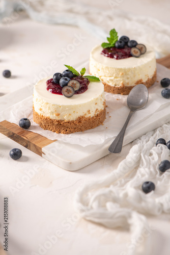 Mini cheesecakes with fresh blueberries and berry compote on a marble board