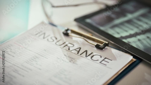 Filling out an insurance form, a professional explains dental treatment coverage. A dentist reviews medical insurance details, ensuring accurate information on healthcare benefits for patient records
