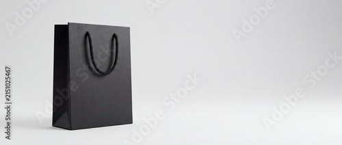 Minimalist black shopping bag with rope handles placed on a plain white background with emphasizing simplicity elegance handles set