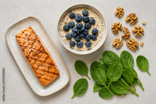Salmon fillet, oatmeal with blueberries, walnuts and spinach on neutral background, clean eating concept.