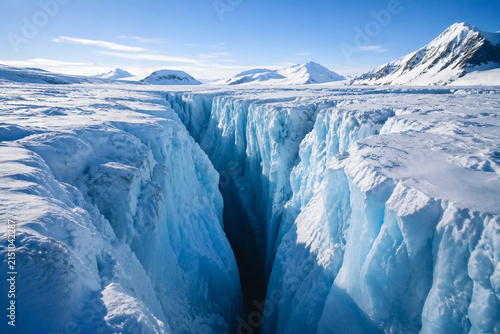 Deep glacier crevasse with blue ice walls in polar landscape, glacial environment and climate concept