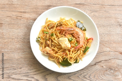 spicy stir fried spaghetti seafood slice squid and shrimp couple clam with chili and basil leaf in Thai tom yum sauce on plate 