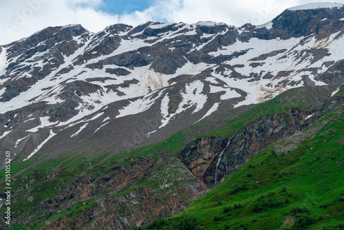 Mountains covered in snow with green valleys below Elbrus