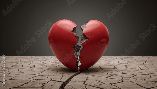 A broken red heart with a cracked surface, symbolizing heartbreak and sadness, rests on dry, cracked earth