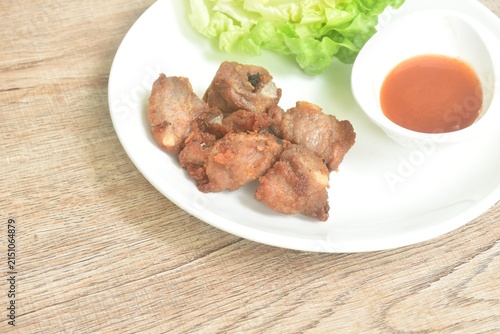 fried fermenting pork cartilage bone with garlic with cos lettuce salad dipping chili sauce on plate