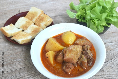 pork curry or Mussamun Indian food with slice potato on bowl eat couple fresh green oak salad and grilled butter toast bread