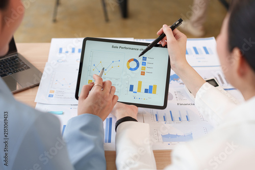 Businesswomen analyzing financial charts on digital tablet during meeting in office