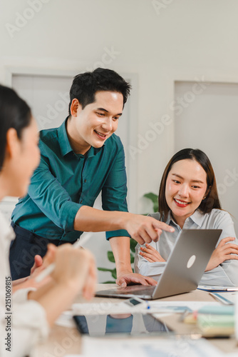 Asian business team working together and smiling at laptop in modern office