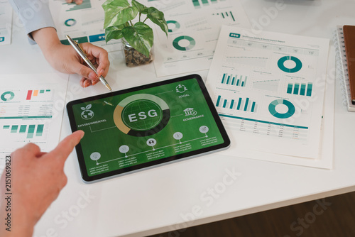 People reviewing ESG data on a digital tablet and financial reports in an office