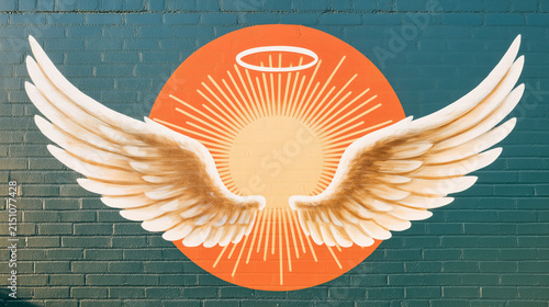 Angel Wings Emblem: A stylized emblem featuring a radiant sunburst, a halo, and a pair of spread angel wings, artfully painted on a brick wall.