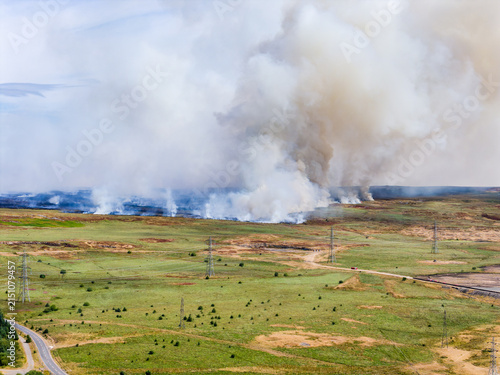 Foto Thick smoke plume rising from grassland wildfire in open countryside, fire line
