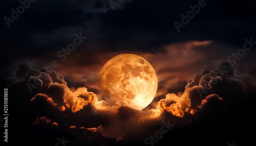 eerie orange moon glows amidst dark hazy clouds in the night sky