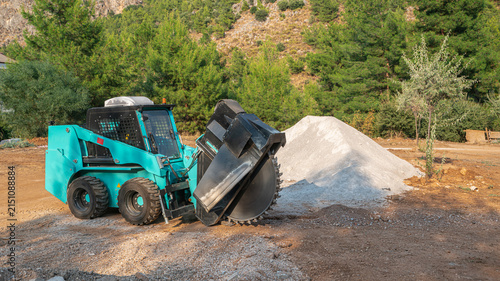 Canvastavla Compact Skid Steer Loader with Wheel Saw Trenching Attachment on a Construction