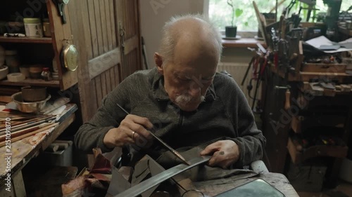 Elderly craftsman working in his old workshop, carefully restoring collectible Japanese bladed weapons