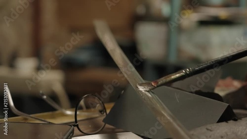 Elderly craftsman working in his old workshop, carefully restoring collectible Japanese bladed weapons