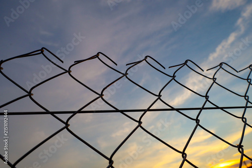 Foto A chain link wire fence stands out clearly against the evening sky during sunset
