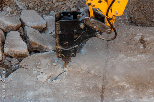 Construction equipment breaks concrete at a work site in broad daylight