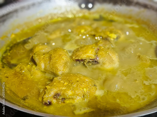 Fotografie Delicious yellow chicken curry simmering in a pan close up