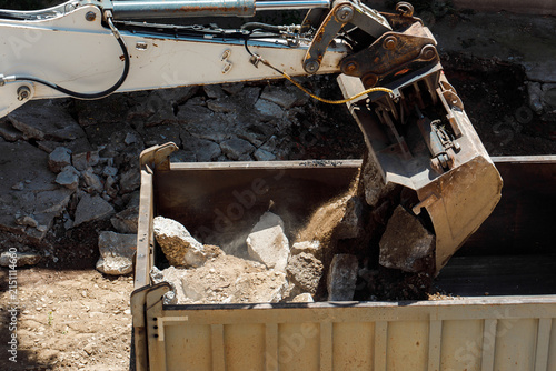 Heavy machinery clears debris from a site into a dumpster
