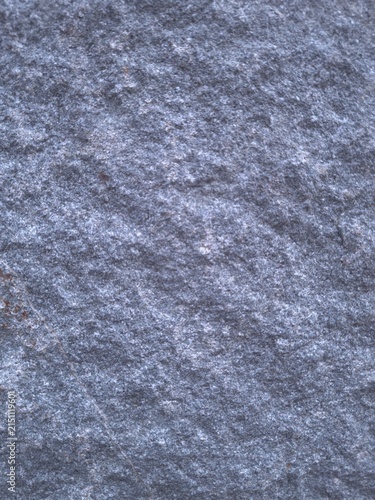 Textured gray stone surface with natural lines and a granular structure. A detailed macro shot showcasing subtle mineral tones and organic patterns, suitable for use in design projects, backgrounds.