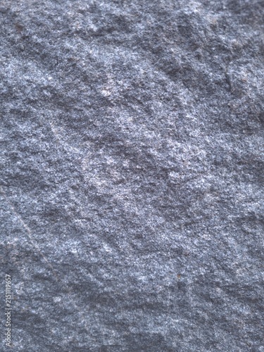 Textured gray stone surface with natural lines and a granular structure. A detailed macro shot showcasing subtle mineral tones and organic patterns, suitable for use in design projects, backgrounds.