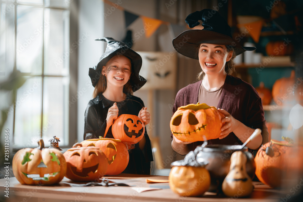 Obraz premium Happy Mother and Daughter Carving Pumpkins Together for Halloween
