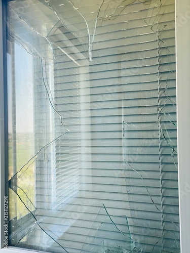 Shattered Glass Pane of a Modern Plastic Window with Blinds After Damage or Impact