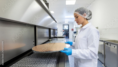 Female worker inspecting food production line in factory