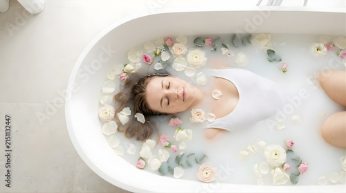 Young woman relaxing in a milk bath with flower petals at a spa