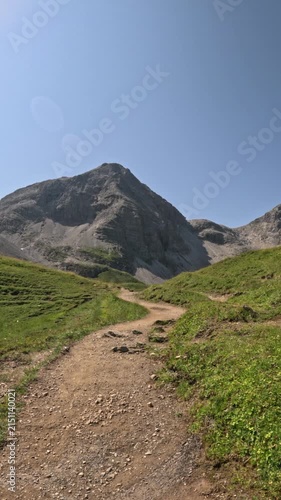 First person view hiking down a winding mountain trail in summer