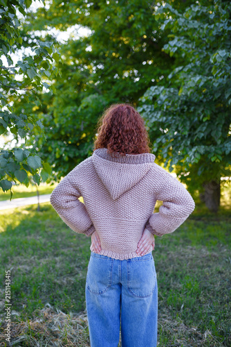 Quadro su tela Redhead teenage girl in chunky knit sweater with hood back view, outdoors