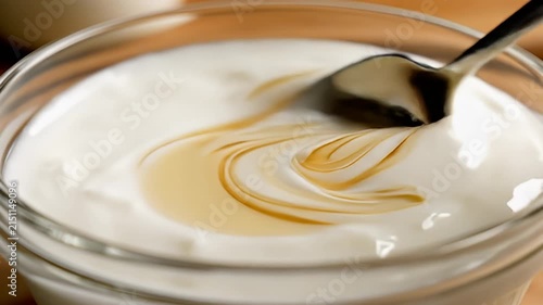 Honey pouring into bowl of fresh yogurt.