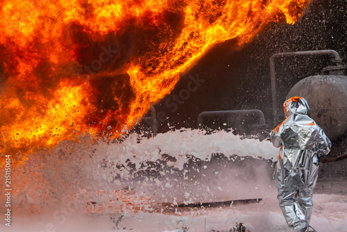 A firefighter risks his life to put out a fire at an oil refinery. The firefighter uses a foam generator to supply foam for extinguishing the fire. The power of fire and the feat of firefighters.
